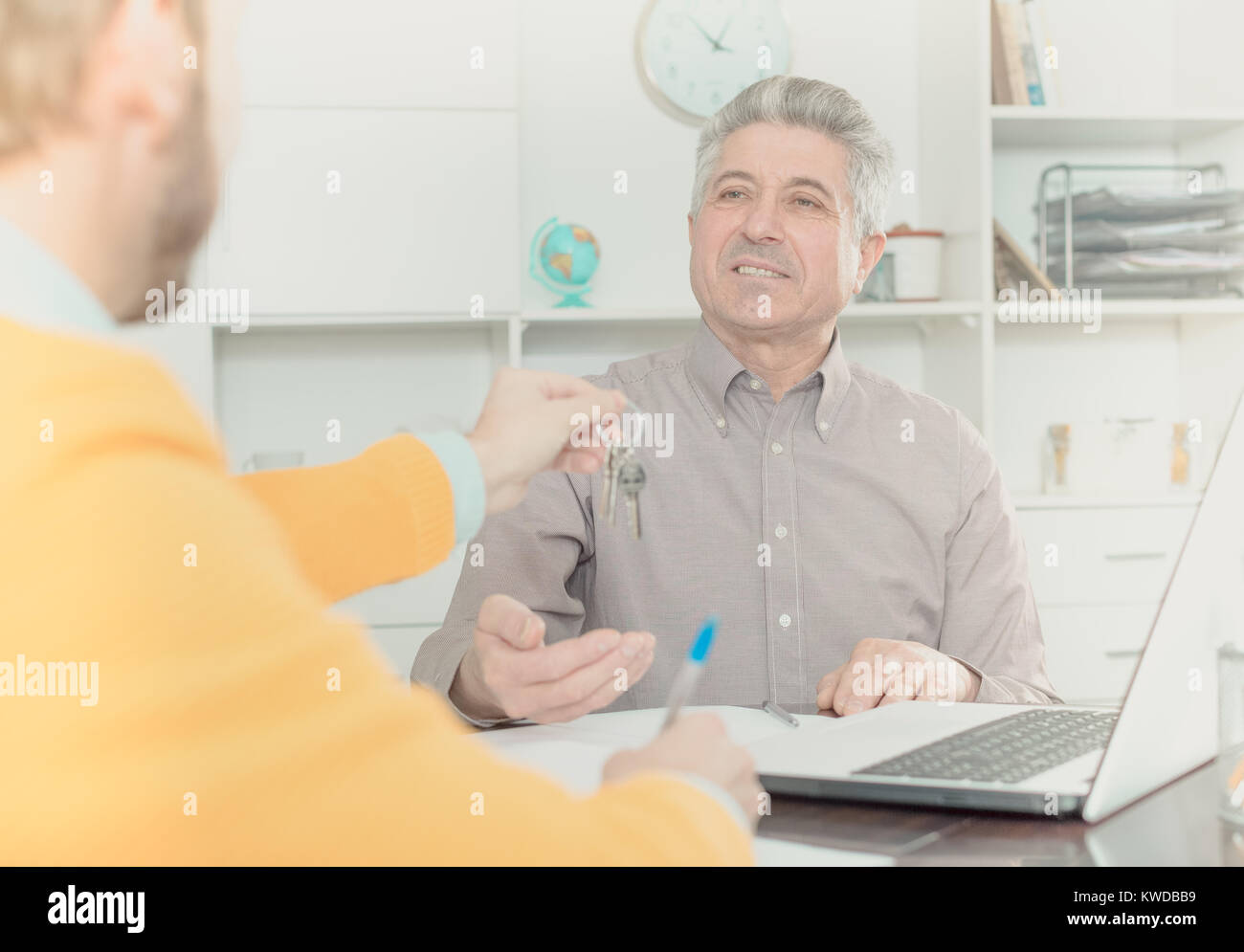 Mature man and young agent sign rental agreement in agency and hand