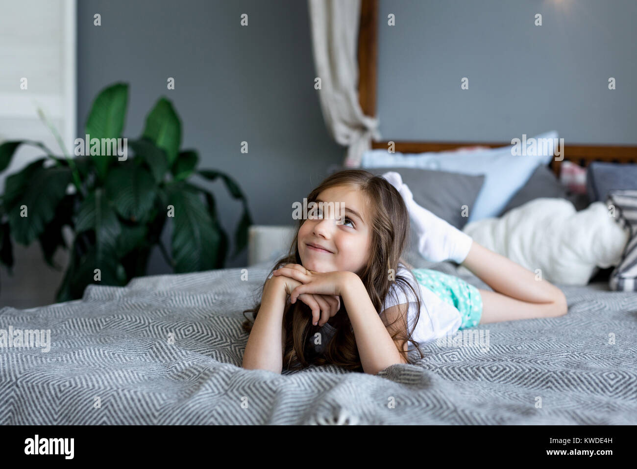 Beautiful little girl lying on bed at house. Portrait of a beautiful
