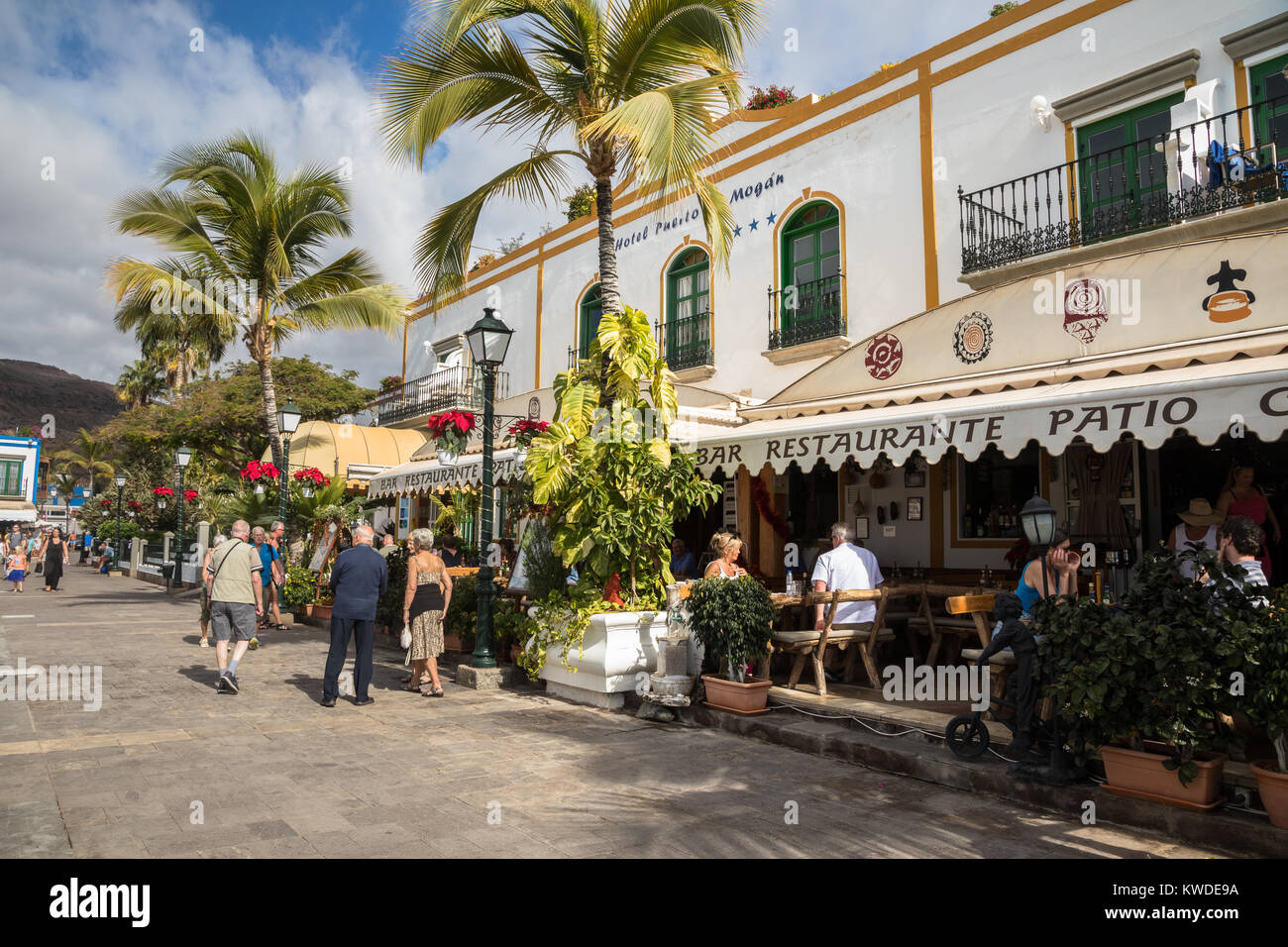 Puerto de Mogan, Gran Canaria in Spain - December 16, 2017: Tourists walking on the promenade and eating at a restaurant in Puerto de Mogan. Stock Photo