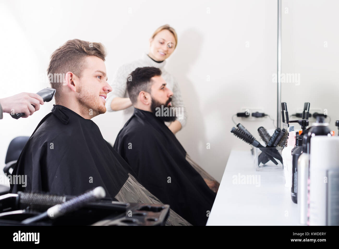 Young Men Clients Waiting For Their Haircuts To Be Finished At