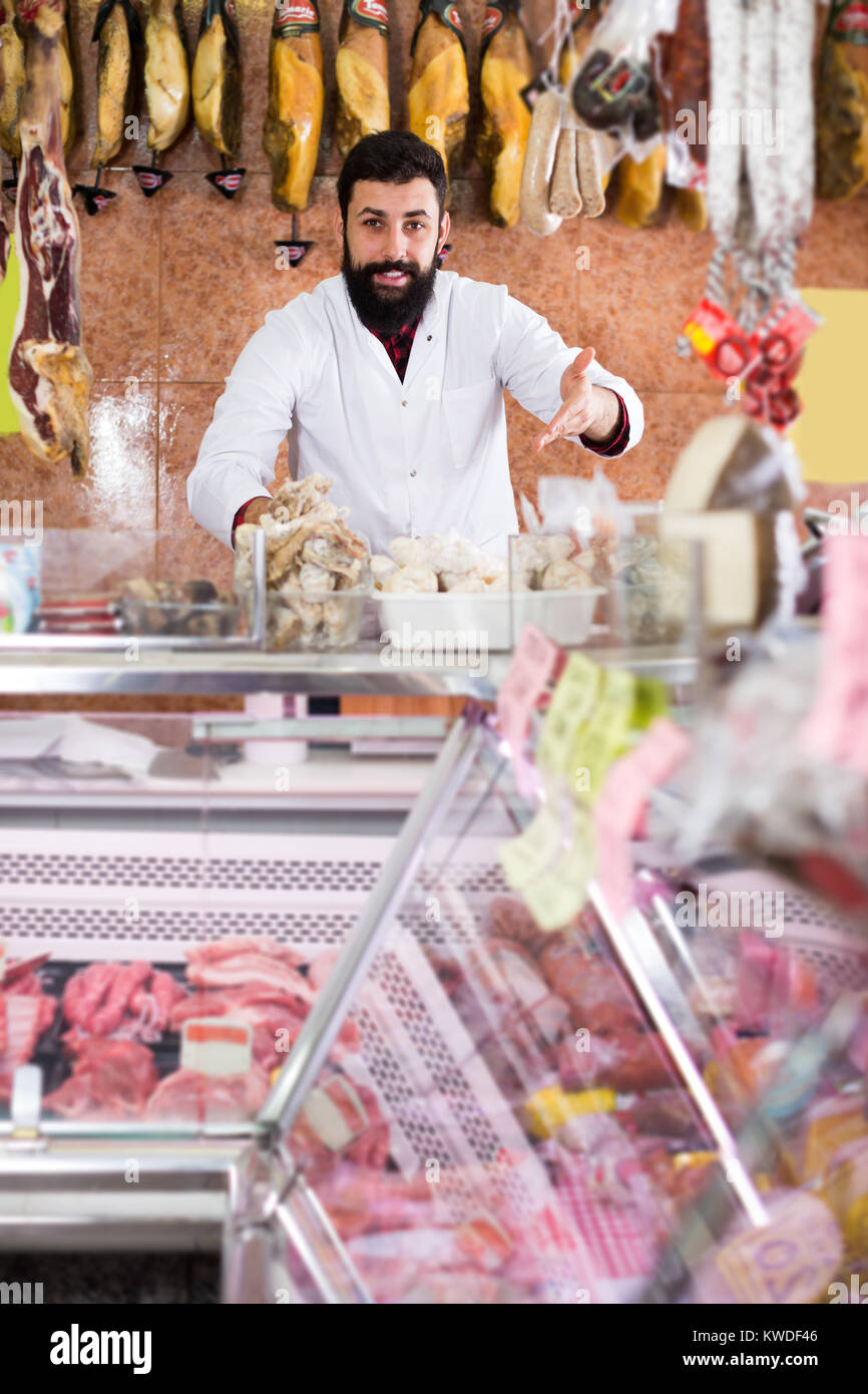 Smiling male seller grouping meat to sell in butcher’s shop Stock Photo ...