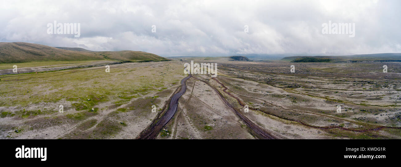 Aerial view overlooking a plain with many gullies and a dirt road at the base of Cotopaxi Volcano in the Ecuadorian Andes. Stock Photo