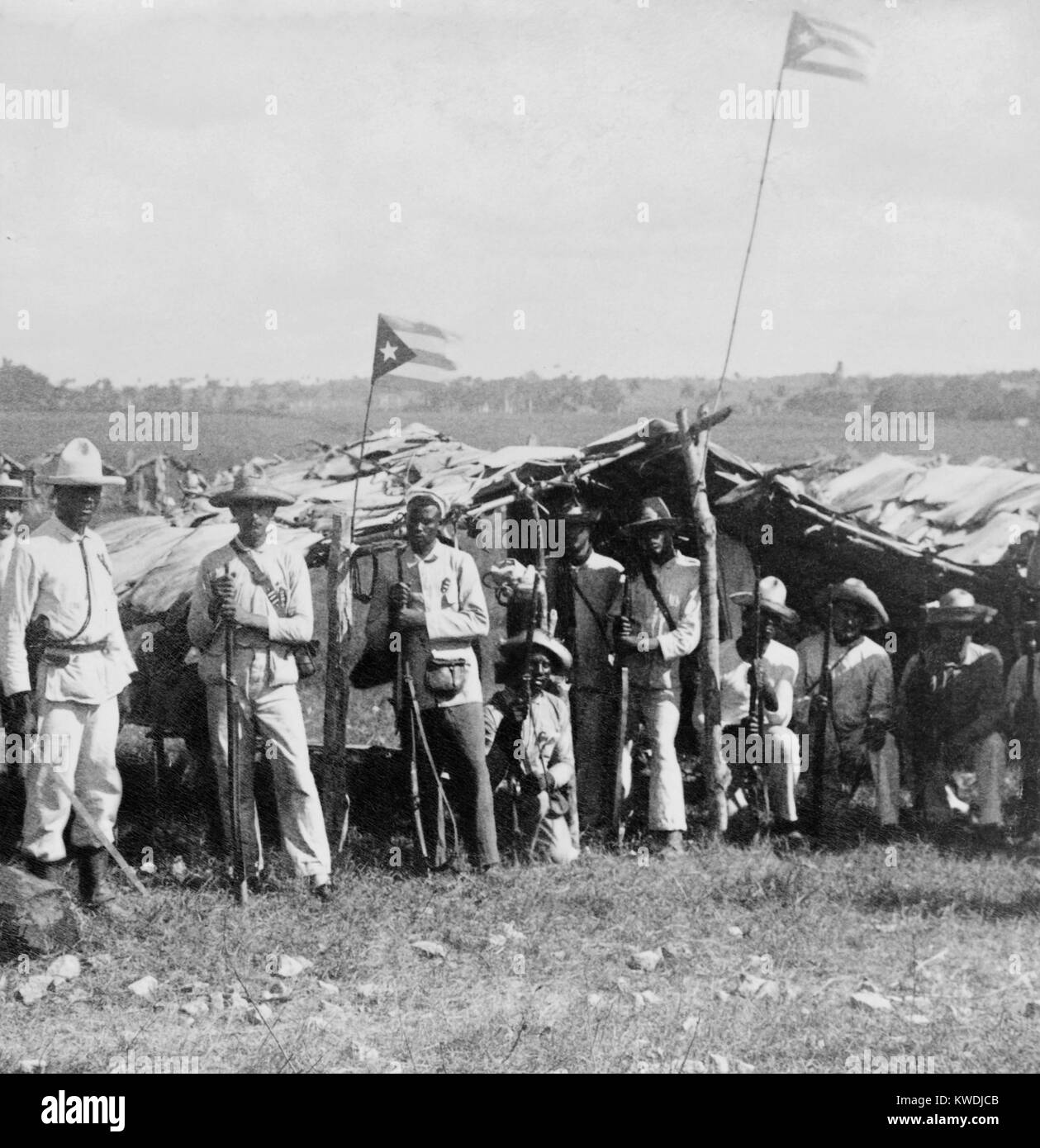 Uniformed Cuban soldiers in the field with their flag and weapons. The multi-racial group is at Guanabacoa, east of Havana, ca. 1899 (BSLOC 2017 10 43) Stock Photo