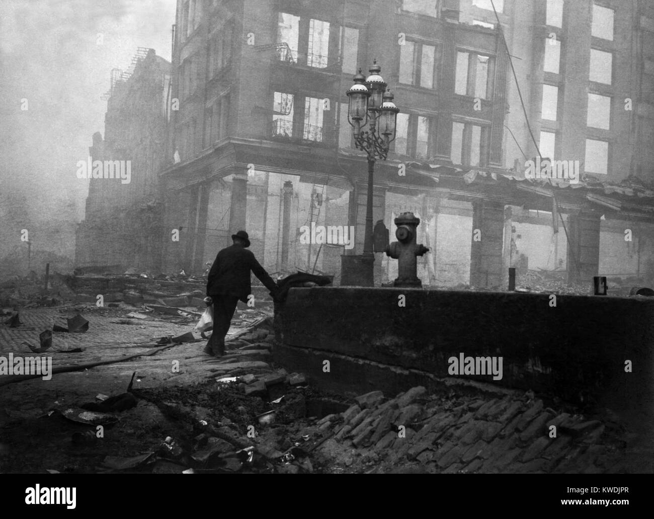 A solitary man walks in the ruins after the April 18, 1906 San Francisco earthquake and 3-day fire. In the foreground is a sunken area on Market Street near Ferry building. April 20, 1906 (BSLOC 2017 17 28) Stock Photo