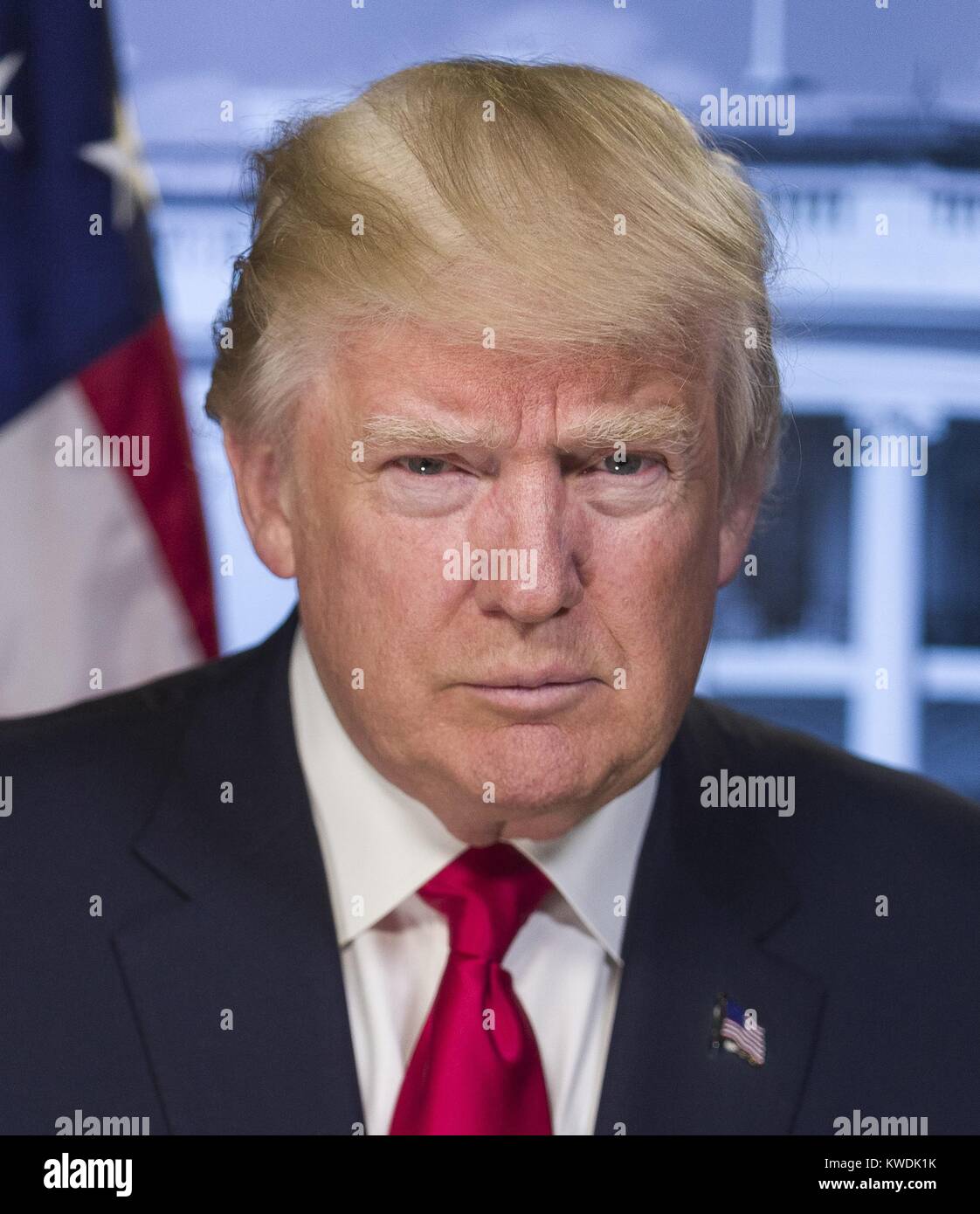 President-elect Donald Trump in a portrait released by the White House on Jan. 20, 2017. Trump is unsmiling, projecting stern and unpleasant emotion. The short focal length causes softening outside the facial plane, but there is no obvious digital retouching. The portrait was likely taken in front of a neutral green screen with the flag and White House added through digital image manipulation (BSLOC 2017 18 152) Stock Photo