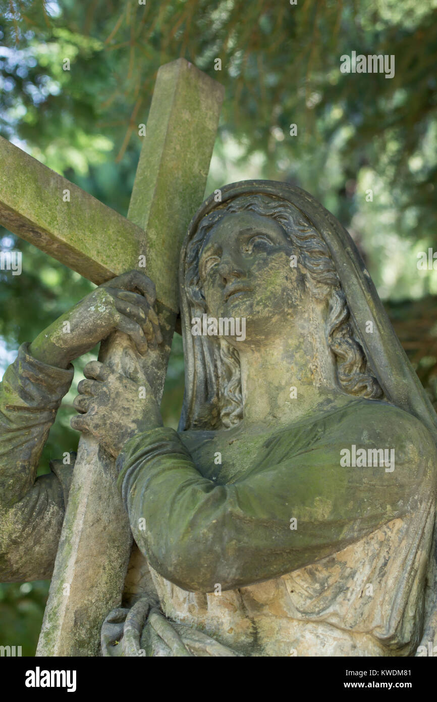 Statue of religious woman holding a cross and looking upon heaven. Old Catholic cemetery, Dresden, Germany. Stock Photo