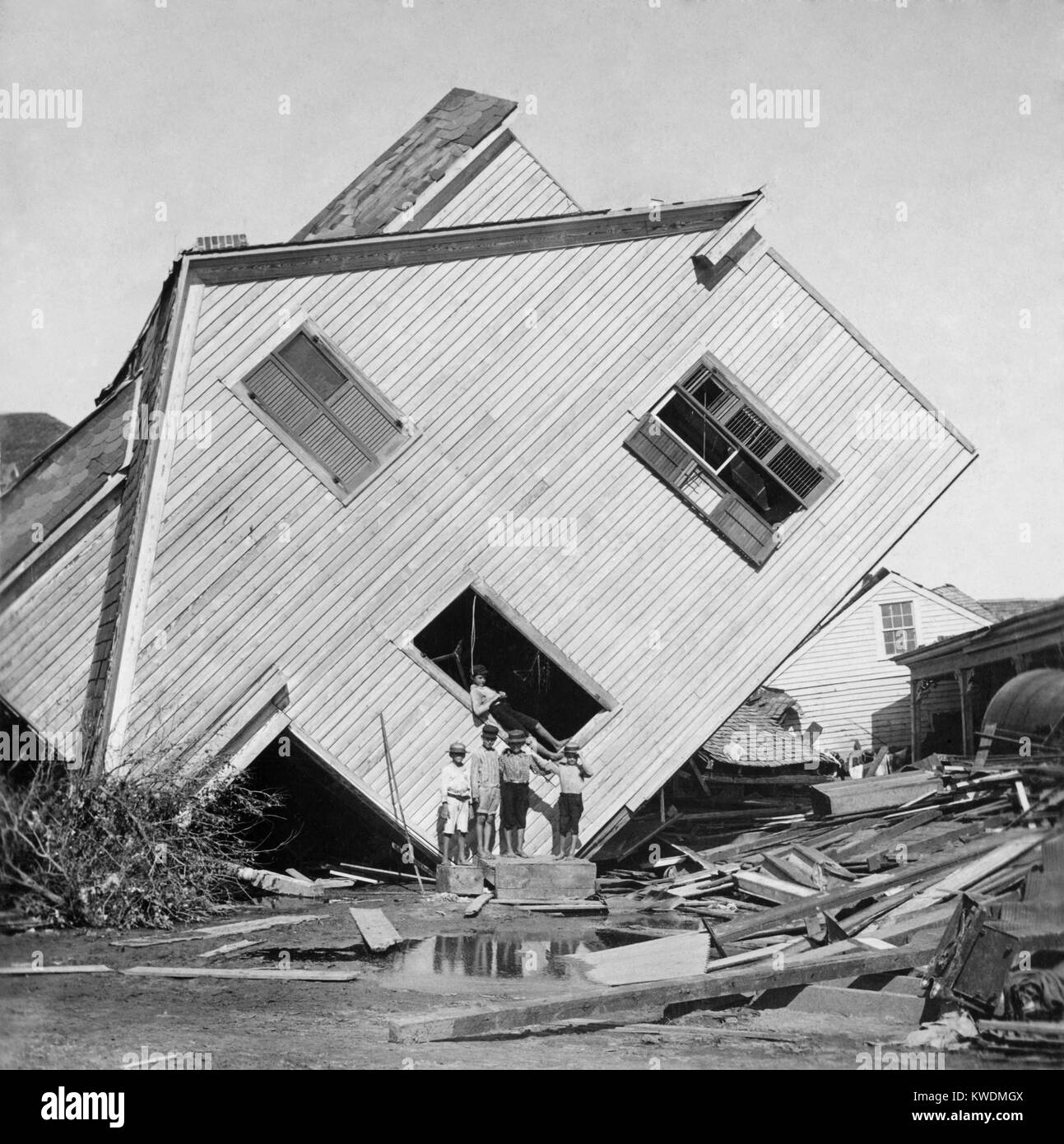 A house tipped on side after the 15 foot storm surge of the Galveston Hurricane of Sept. 1900. Five boys pose in front of the house on Avenue N (BSLOC 2017 17 88) Stock Photo