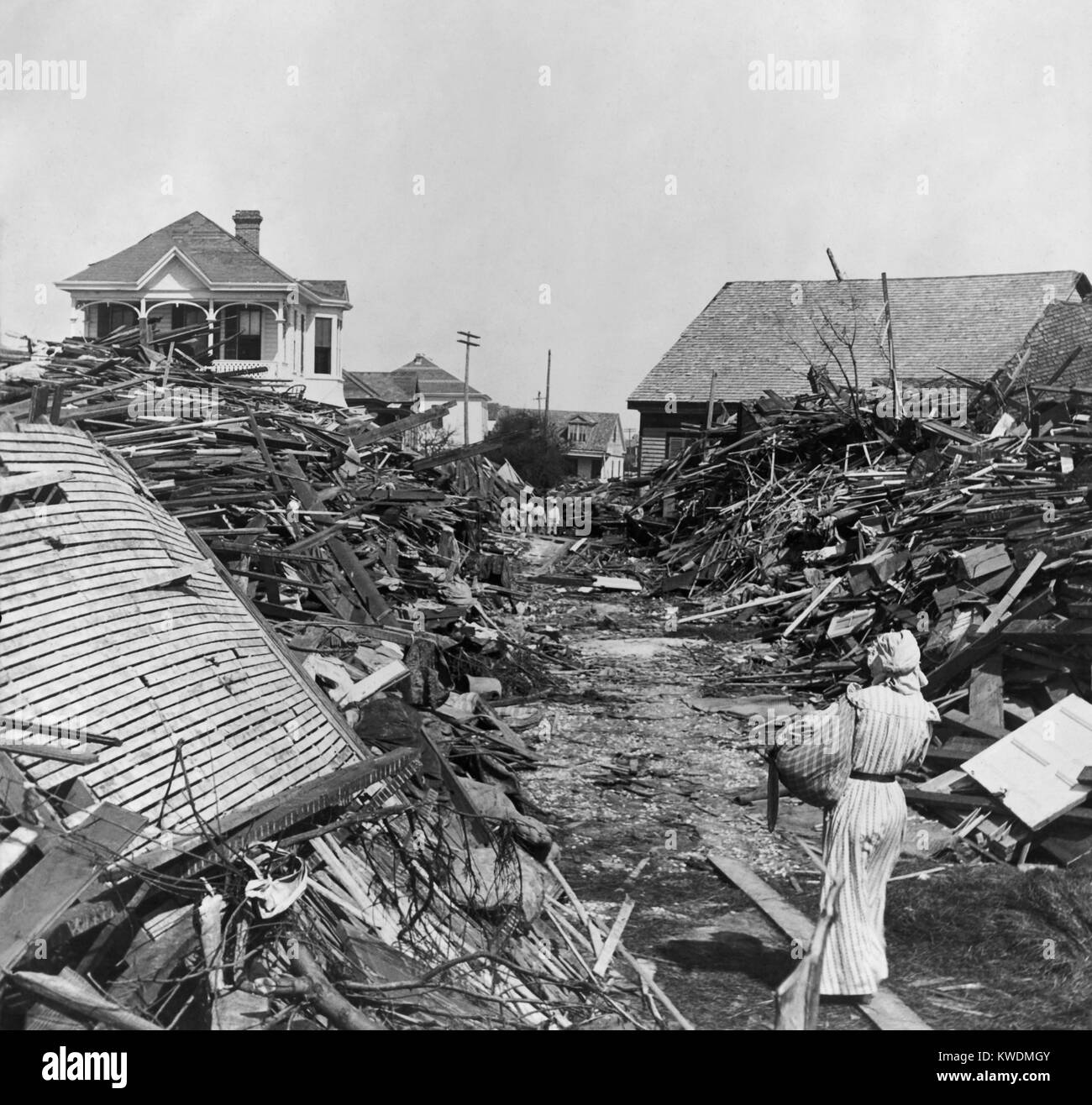 A woman walks through a passageway opened in the debris, on 19th Street, Galveston, Texas. In the distance stand homes spared complete destruction during the Galveston Hurricane of Sept. 1900 (BSLOC 2017 17 89) Stock Photo