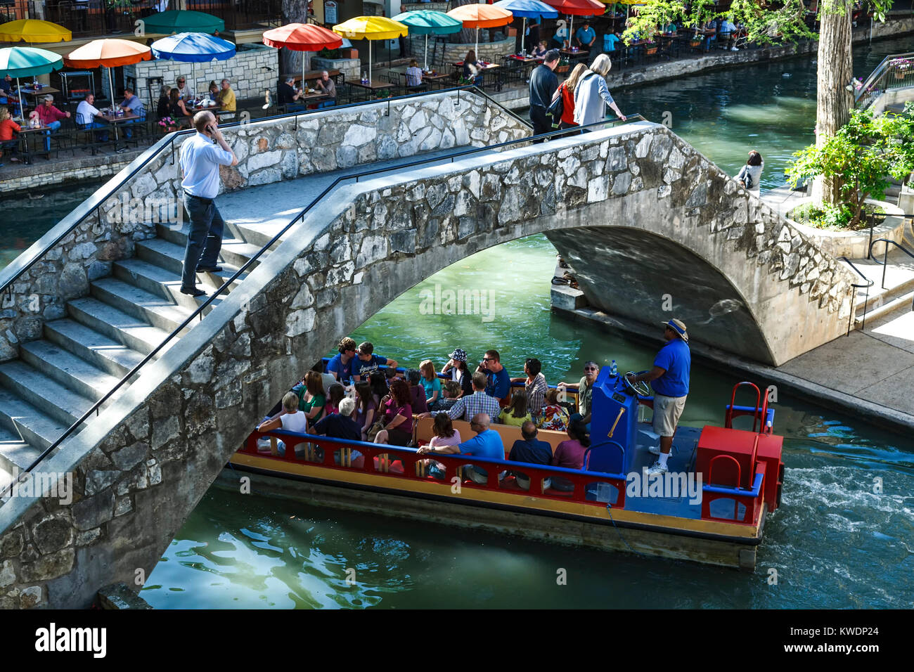 Tourist boat going under bridge on San Antonio River along the Riverwalk, San Antonio, Texas USA Stock Photo