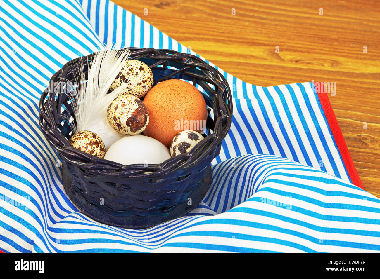 Various eggs in the blue basket on the kitchen apron Stock Photo