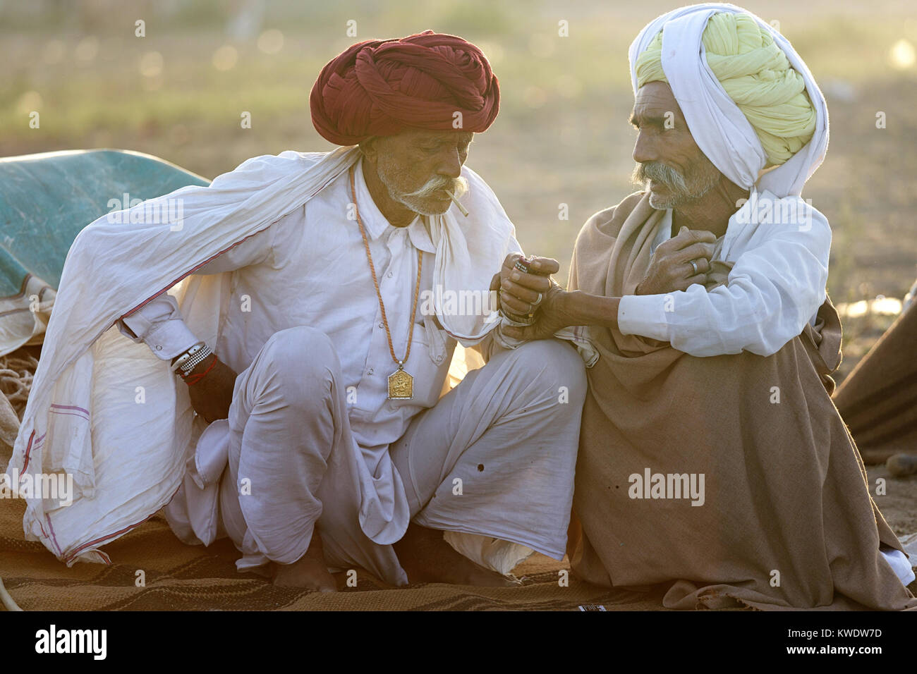 Scene at Pushkar Camel Fair, senior traders wearing turbans sitting by a fireplace, talking and smoking, Pushkar, Rajasthan, India Stock Photo