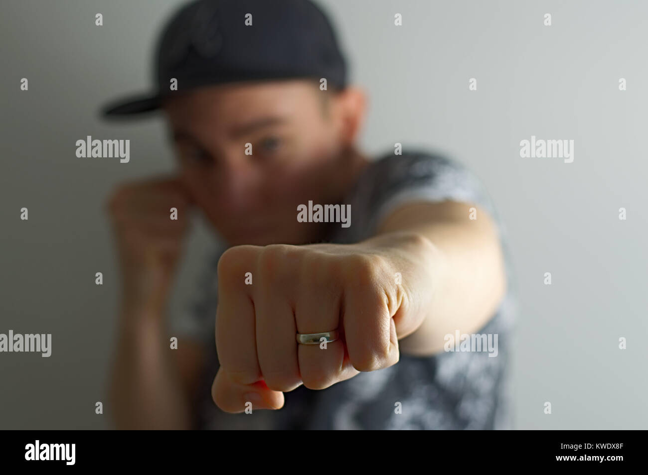 Man wearing baseball cap and wedding ring punching towards camera with only  his fist in focus Stock Photo - Alamy
