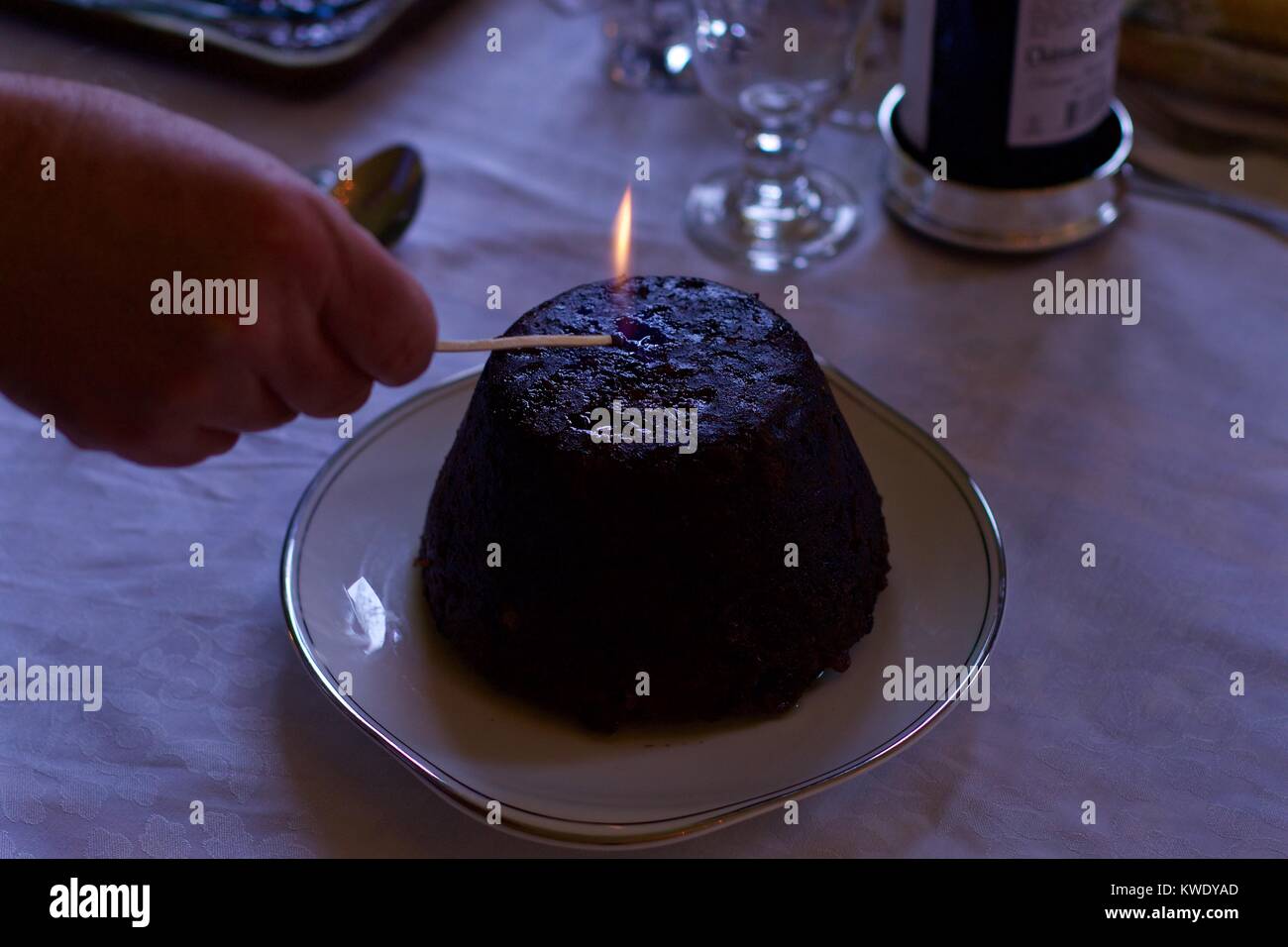 Man's hand lighting christmas pudding Stock Photo