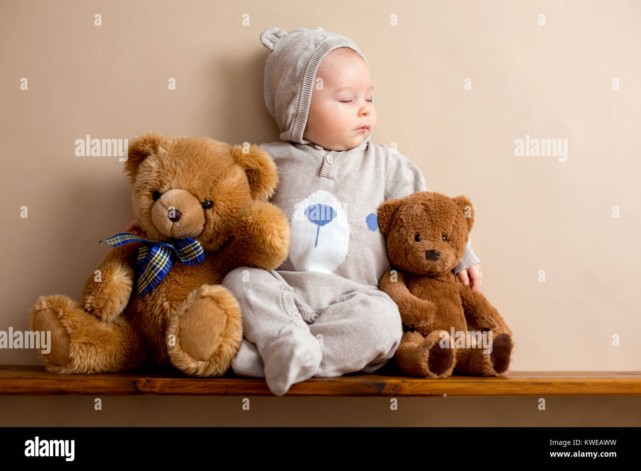 Sweet baby boy in bear overall, sleeping on a shelf with teddy bears  stuffed toys. Shot in studio on creamy background, shot from above Stock  Photo - Alamy