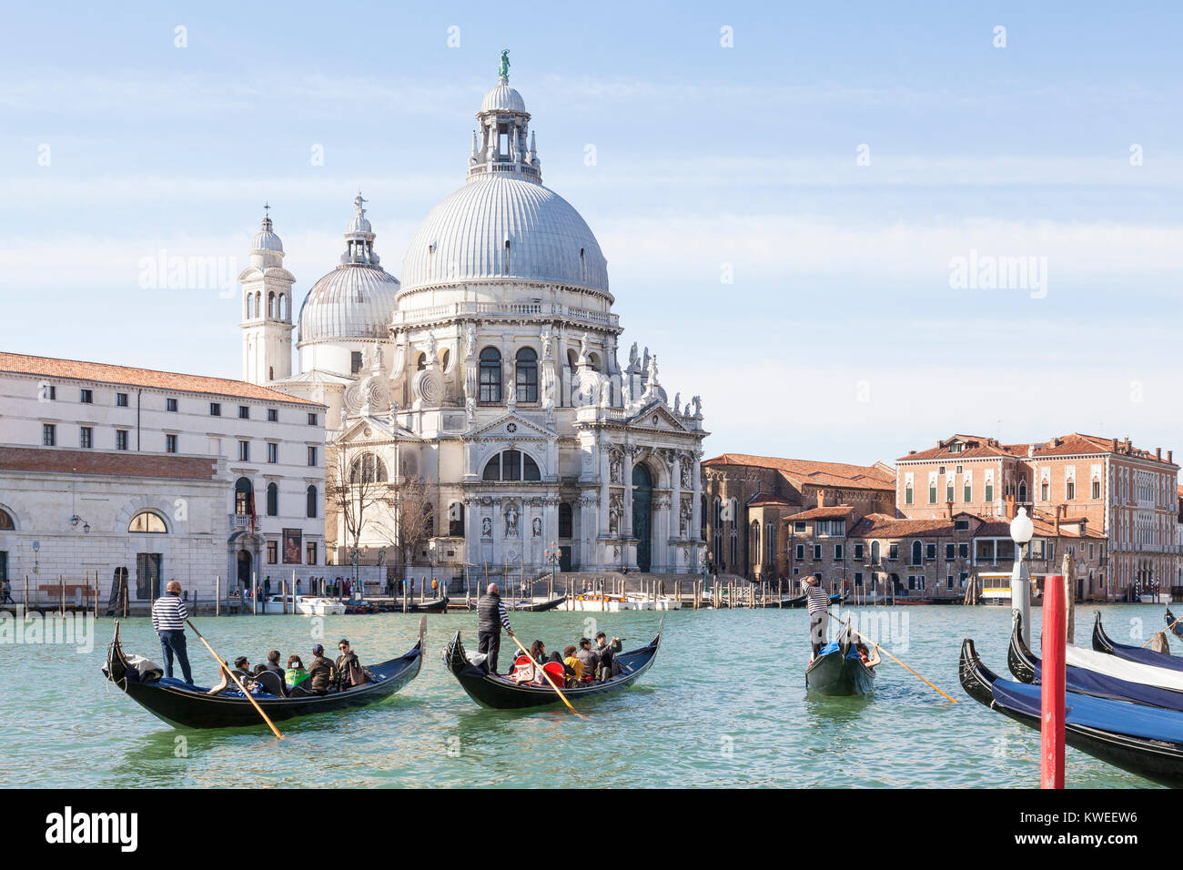 Gondolas with Asian tourists on the Grand Canal in front of Basilica di Santa Maria della Salute, Venice, Italy on a winter morning Stock Photo