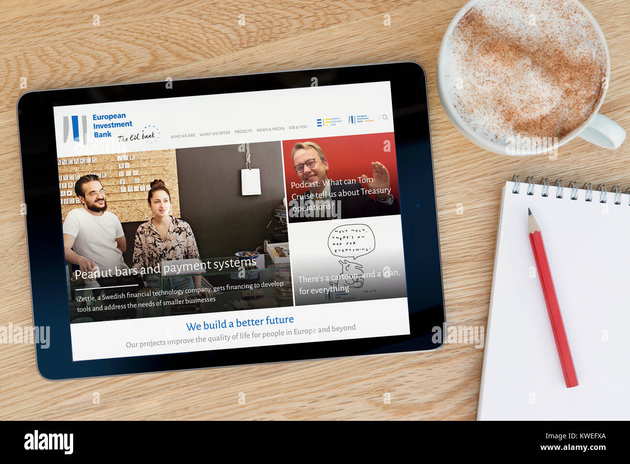 The EIB (European Investment Bank) website on an iPad tablet device,  resting on a wooden table beside a cup of coffee (Editorial only Stock  Photo - Alamy