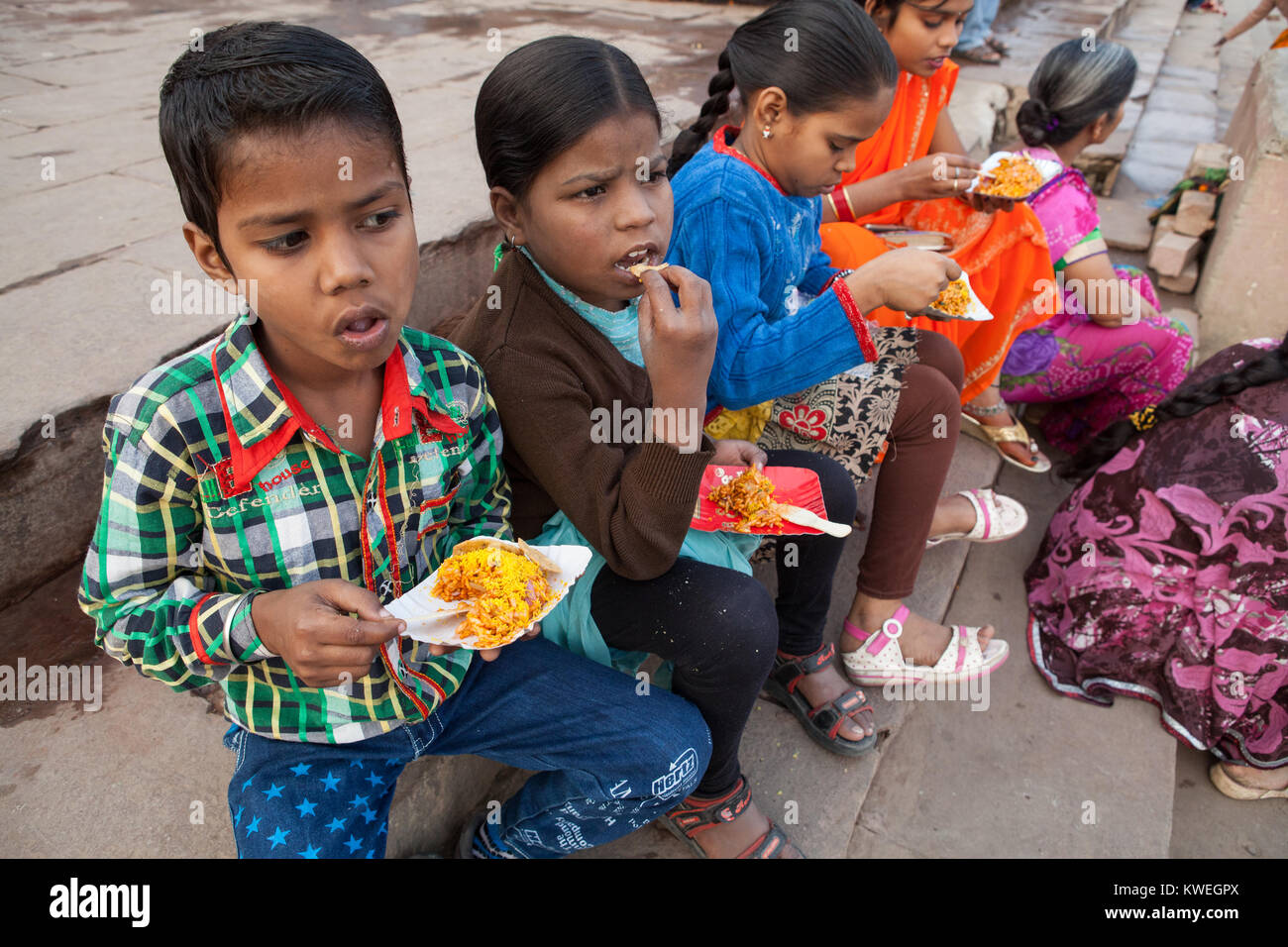 Children eat a snack of bhel puri on the ghats at Varanasi in India Stock Photo