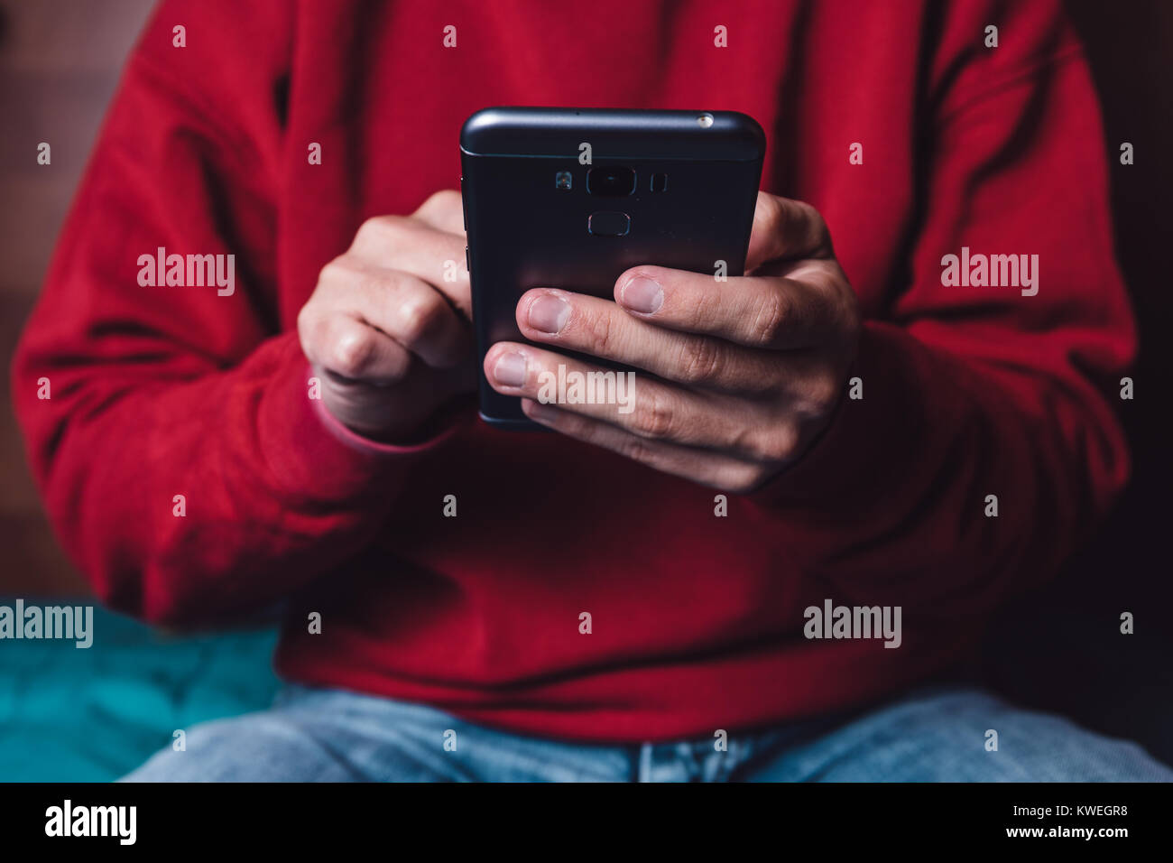 Caucasian male holding the smartphone with the left hand and touching in the touchscreen with one finger of the right hand. Stock Photo