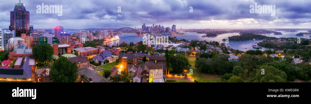 Panorama of SYdney city CBD from North Sydney office towers and high-rises at sunset across blurred blue sydney harbour waters towards major australia Stock Photo