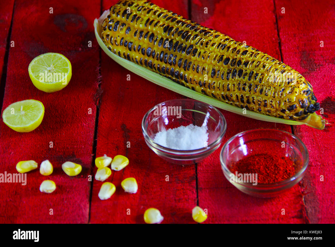 Table top with roasted maize corn, corn grains, lemon, salt and chili