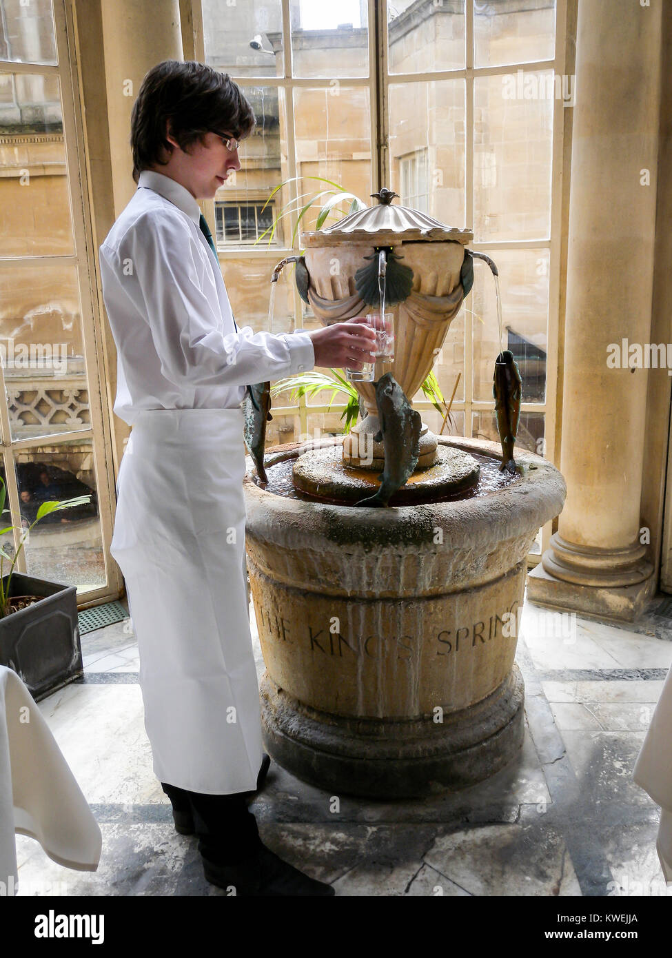 Young man serving mineral water at Roman Baths, City of Bath, Somerset