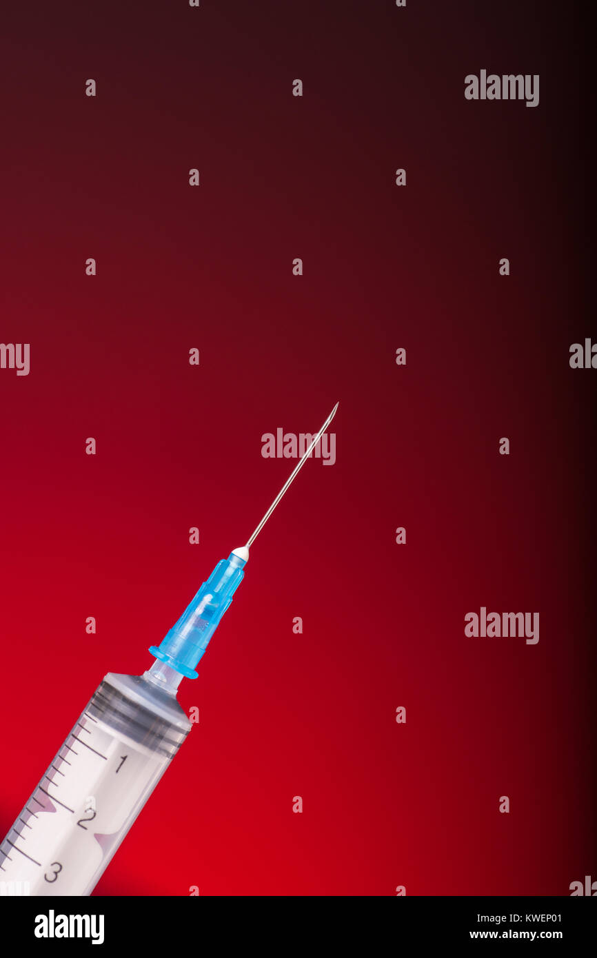 Isolated medical syringe on red, dark background Stock Photo