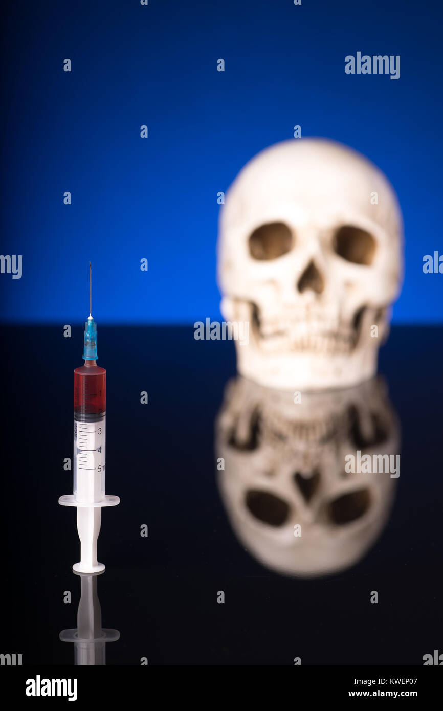 Blurry Skull and syringe, isolated on black blue background with glossy reflection Stock Photo