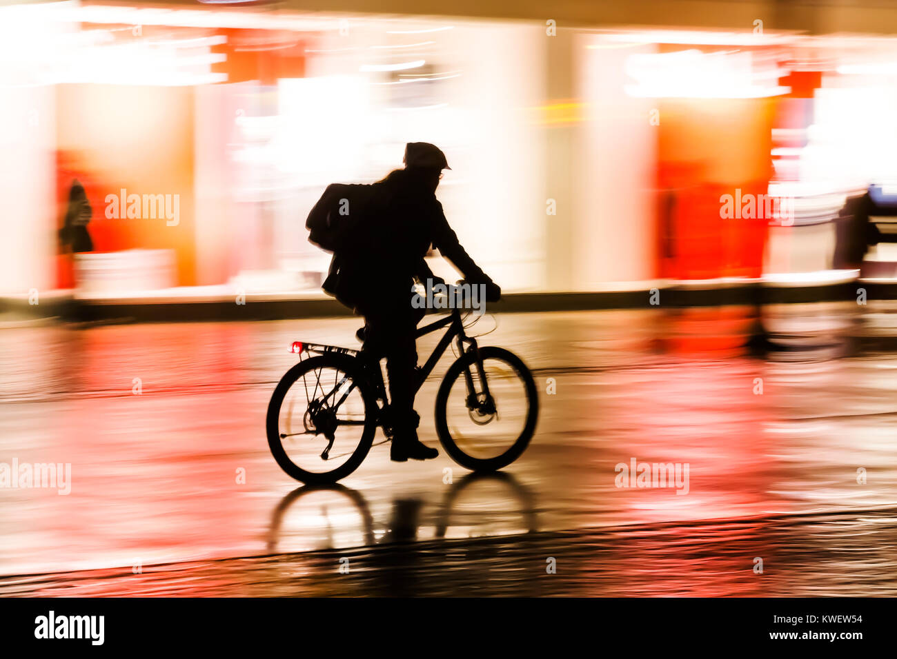 silhouette of a bicycle rider at night with camera made motion blur ...