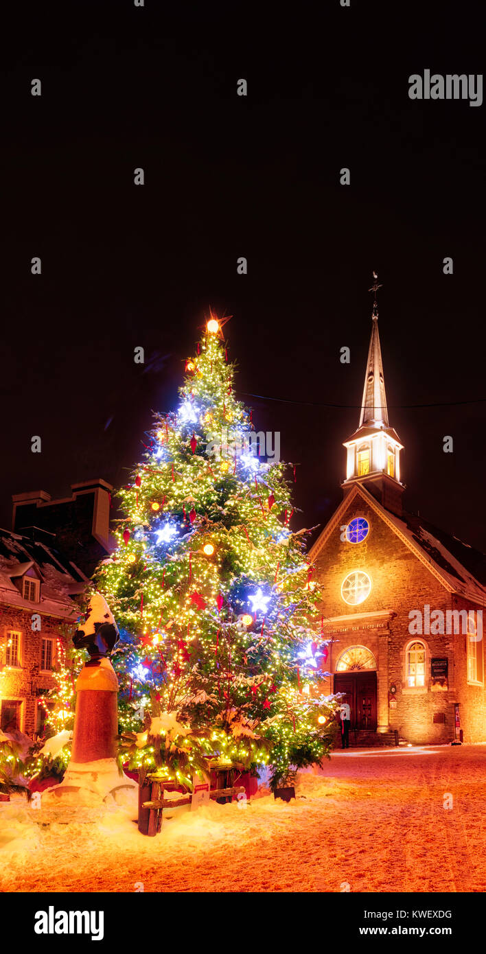 Christmas decorations and fresh snow in Quebec City's Petit Champlain area at night - in Place Royale with the church Eglise Notre Dame des Victoires Stock Photo