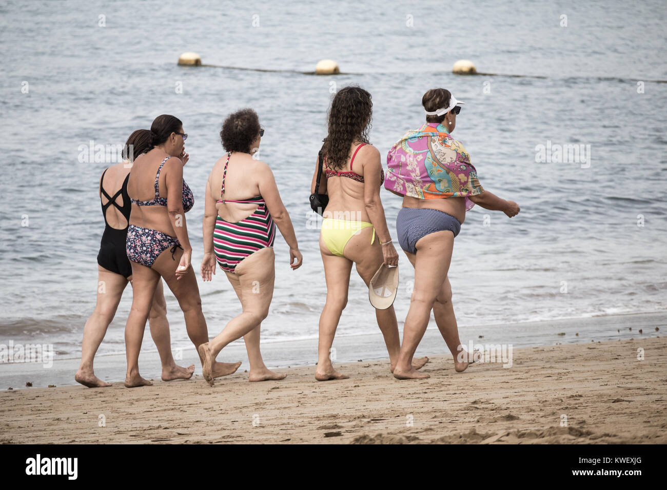 Local Spanish women in swimming costumes walking on beach in Spain Stock Photo