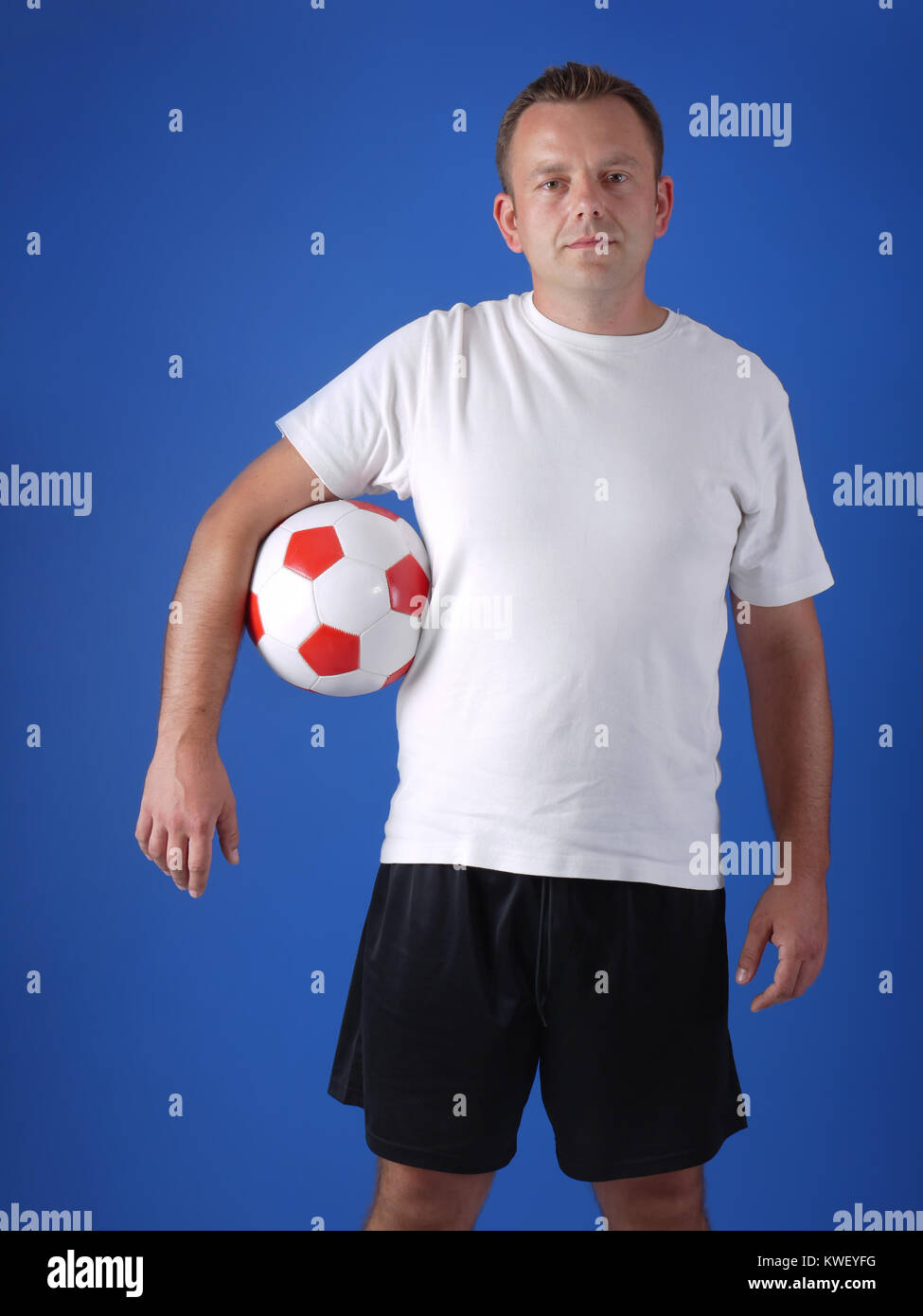 Soccer player wearing white tshirt and black shorts posing with soccer