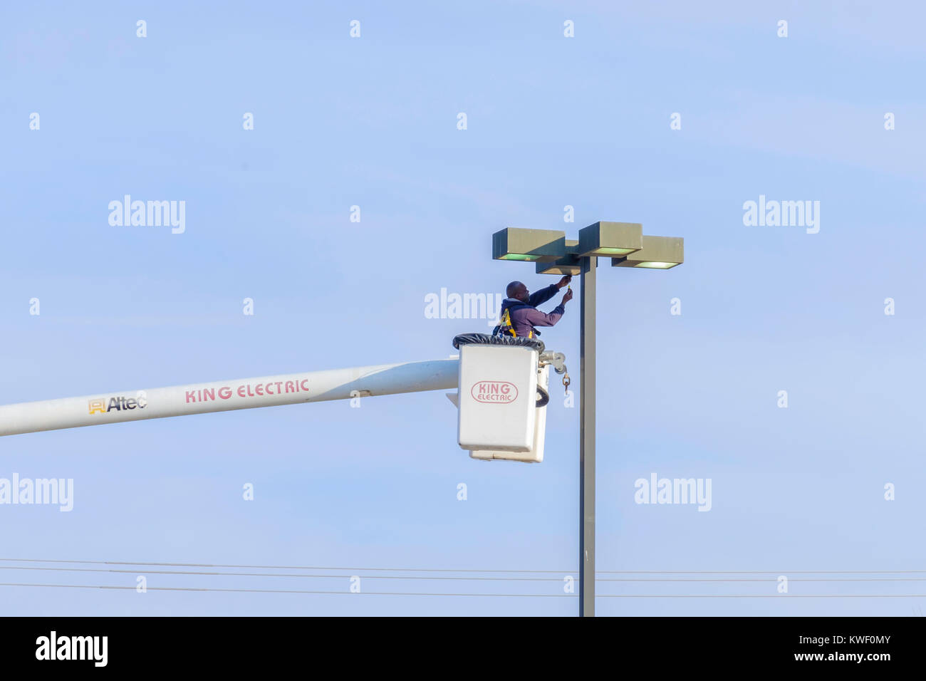 A workman in a lift bucket works on a shopping mall light fixture. Oklahoma City, Oklahoma, USA. Stock Photo