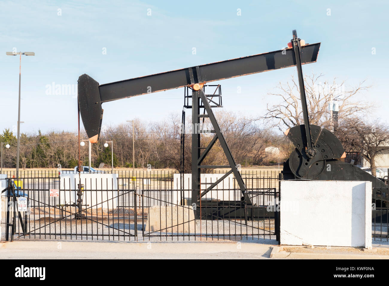 A pump jack pumping oil in the middle of a parking lot at a shopping