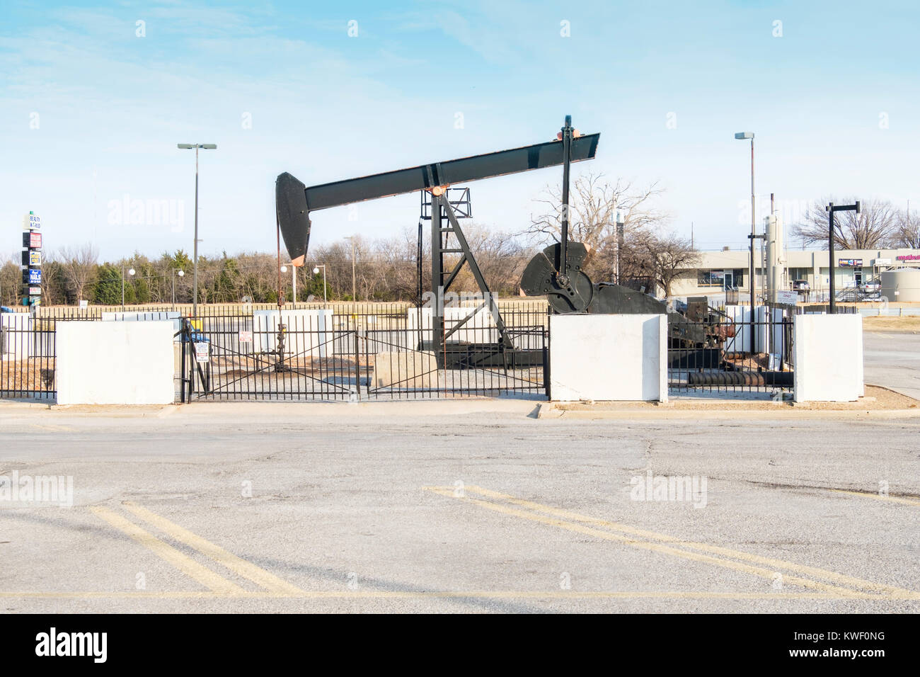A pump jack pumping oil in the middle of a parking lot at a shopping
