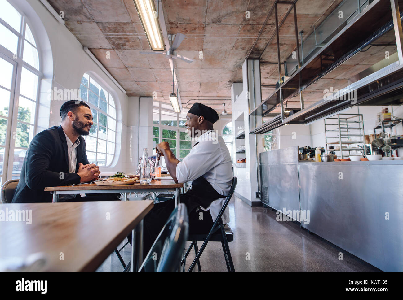Restaurant manager talking with a professional chef. Cafe owner and cook sitting at a table and talking. Stock Photo
