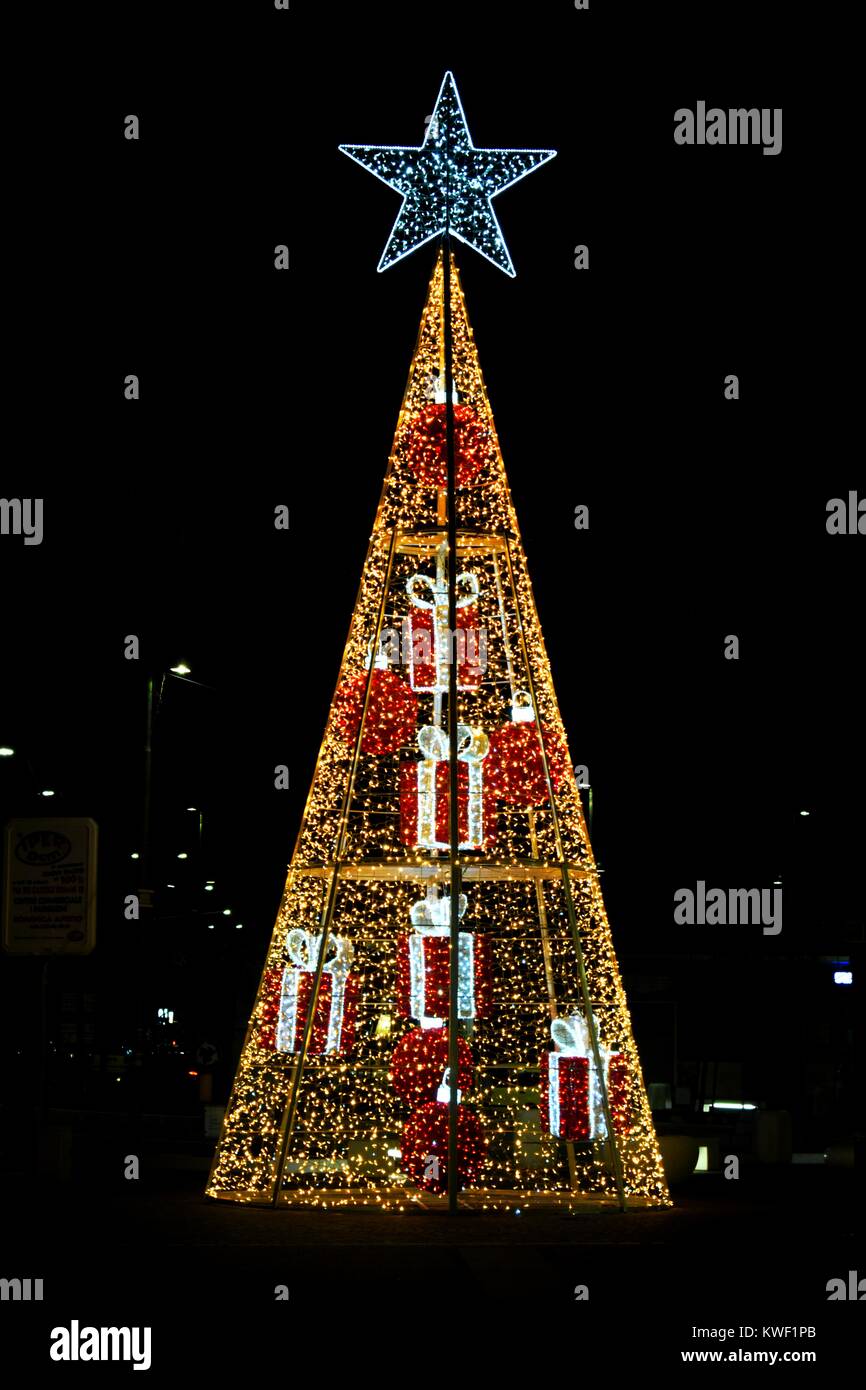 Bright stylized Christmas tree with a star at the top along a city ...