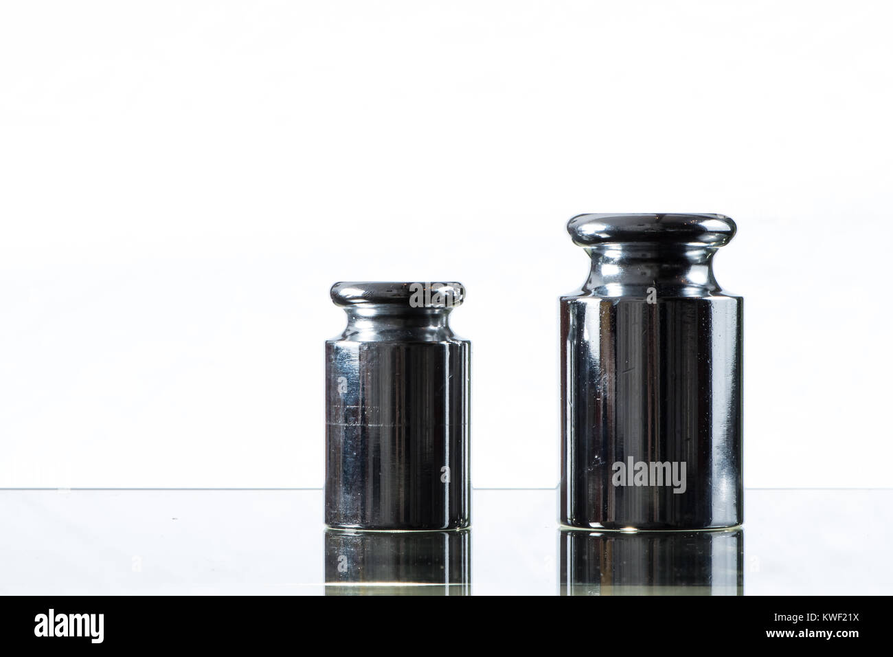 Closeup of two metal weights for calibrating weighing scales, white