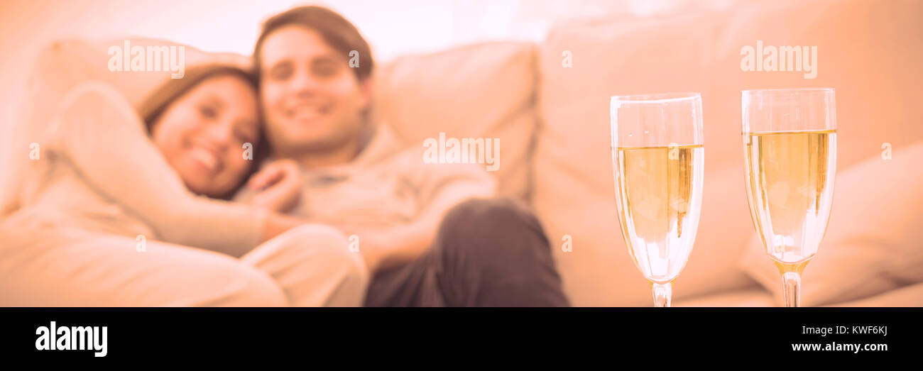 Couple resting on a couch with flutes of champagne Stock Photo