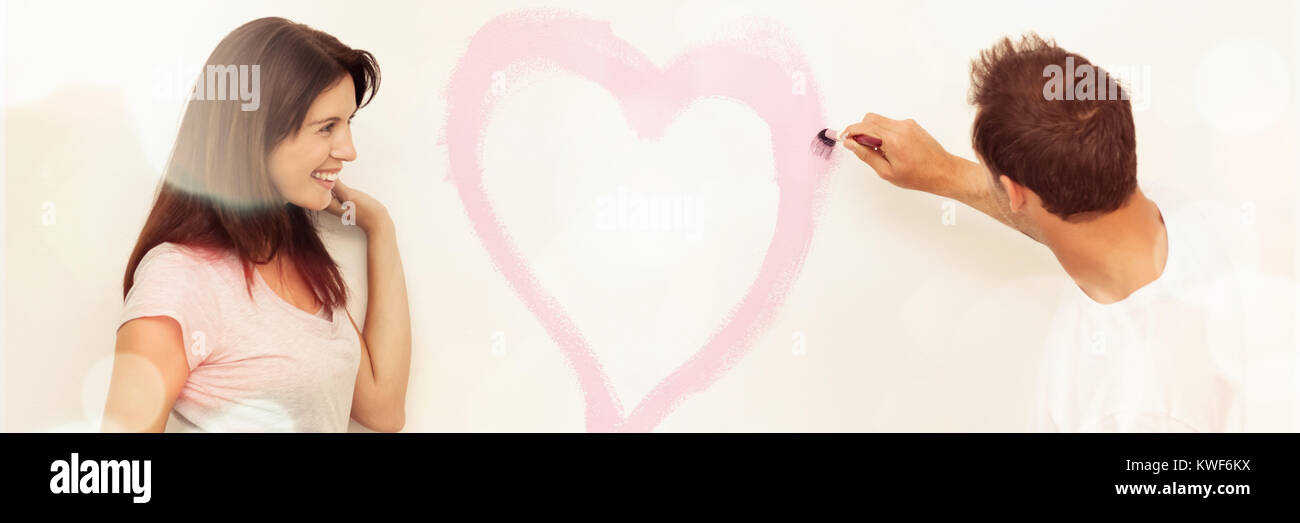 Cute woman looking at her boyfriend painting heart Stock Photo