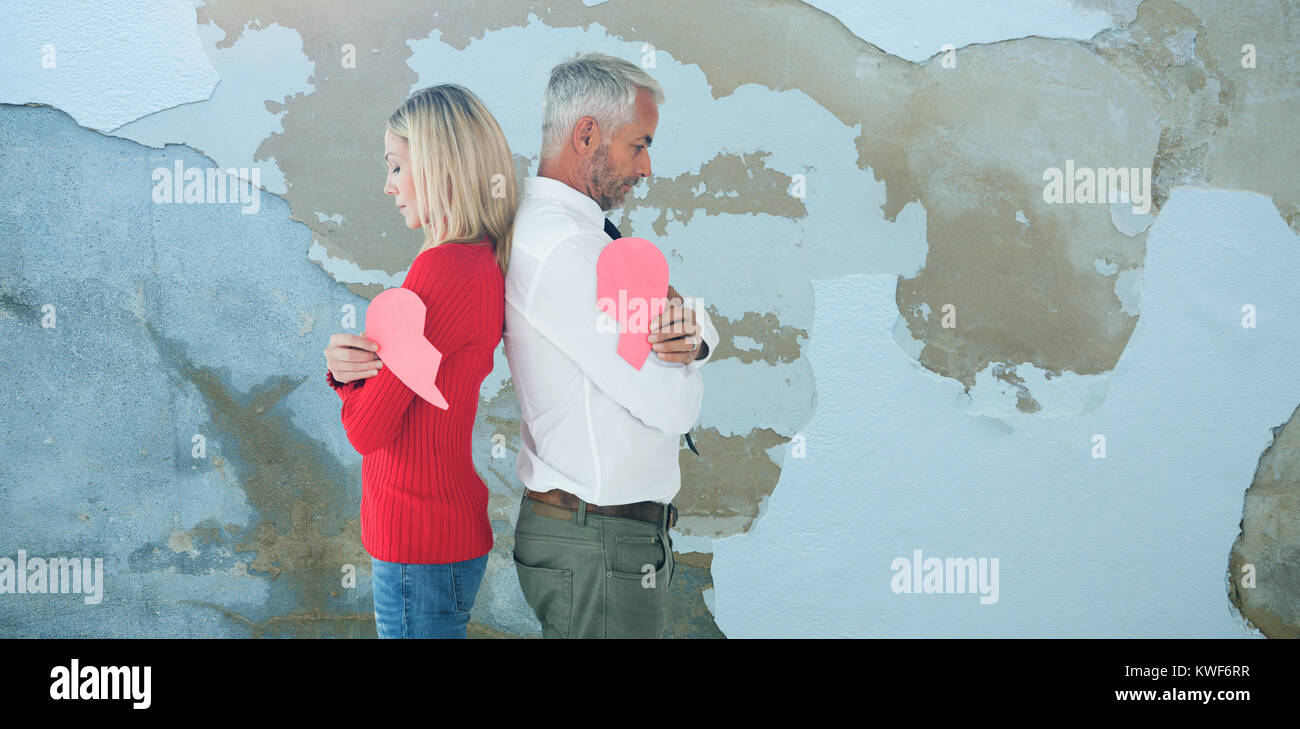 Composite image of couple holding two halves of broken heart Stock Photo