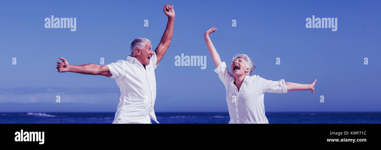 Senior couple jumping at the beach Stock Photo