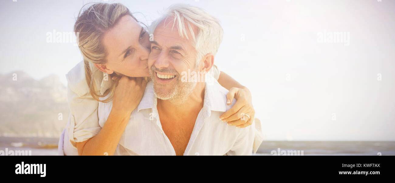 Man giving his smiling wife a piggy back at the beach Stock Photo
