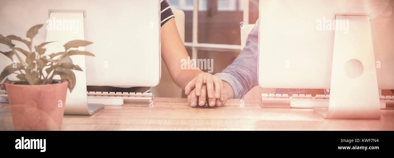 Couple working on computers and holding hands Stock Photo - Alamy