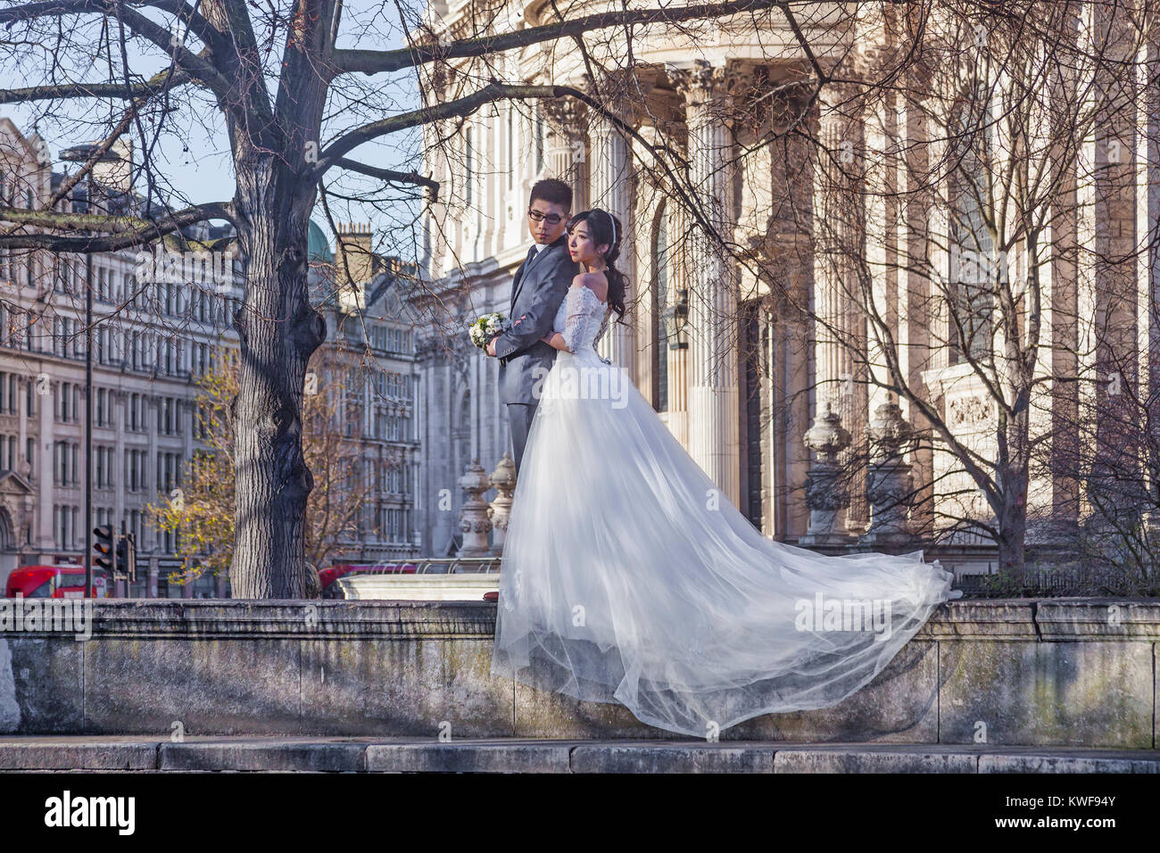 A young Japanese couple posing for wedding photographs in St Paul's Cathedral Garden Stock Photo