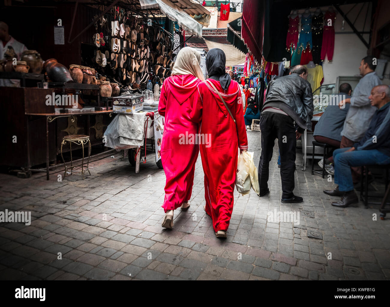 Two red clad local girls in Djellabas shopping in the souk. Stock Photo