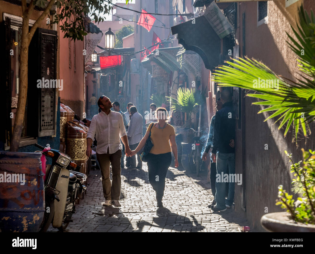 Atmospheric back streets of medina with palms and people. Stock Photo