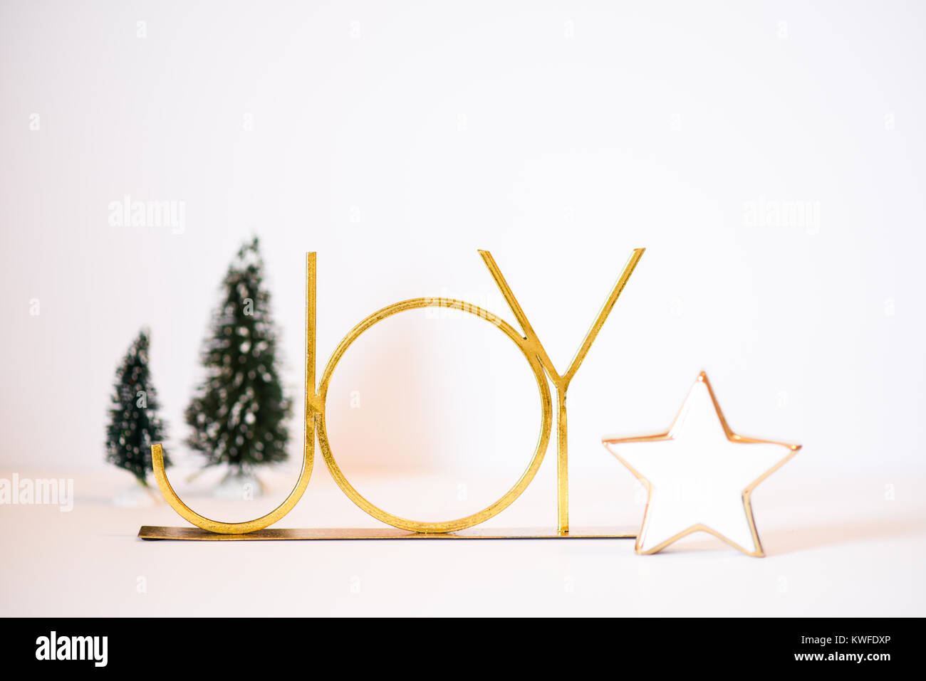 Christmas Scene featuring a gold JOY, cream star, and Christmas trees Stock Photo
