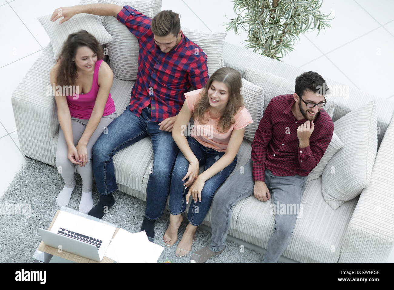 triumphant group of friends laughing while sitting on the couch in the ...