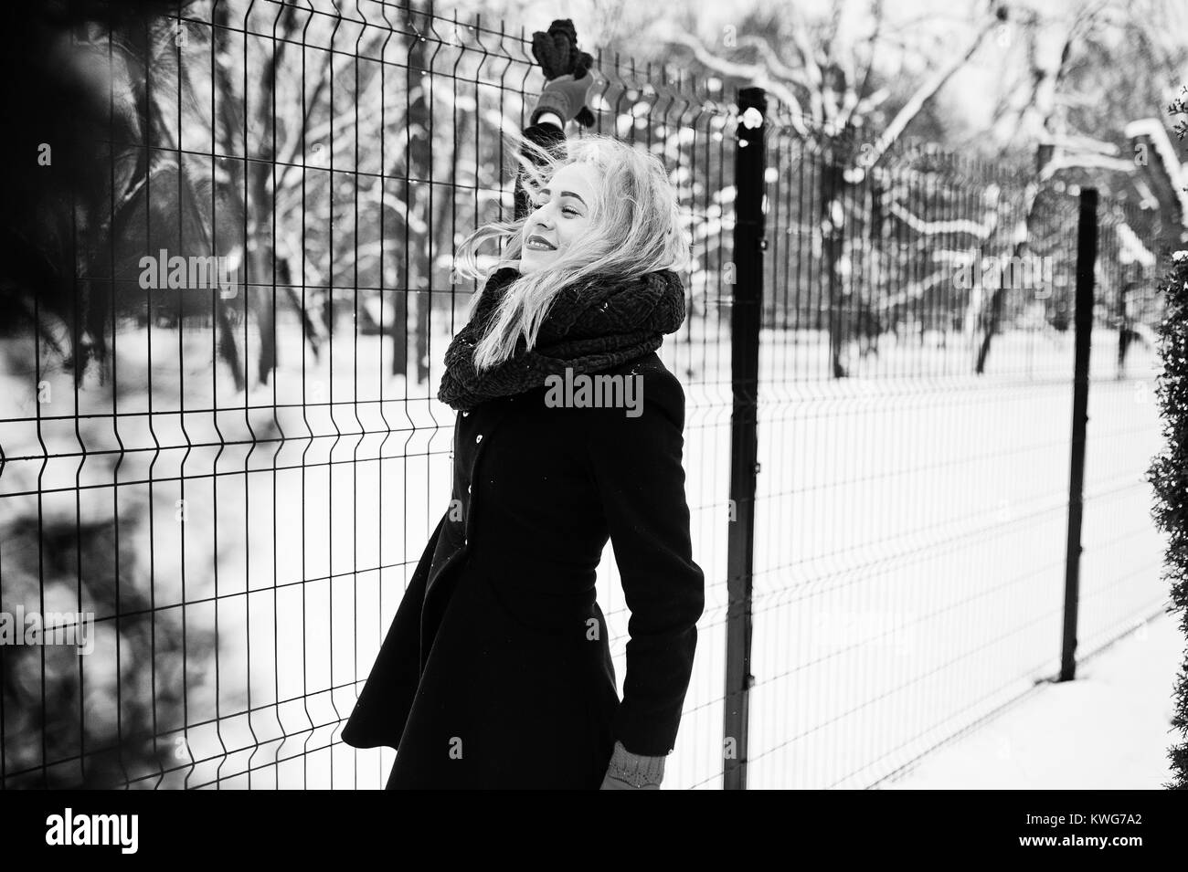 Blonde girl in red scarf and coat walking at park on winter day Stock