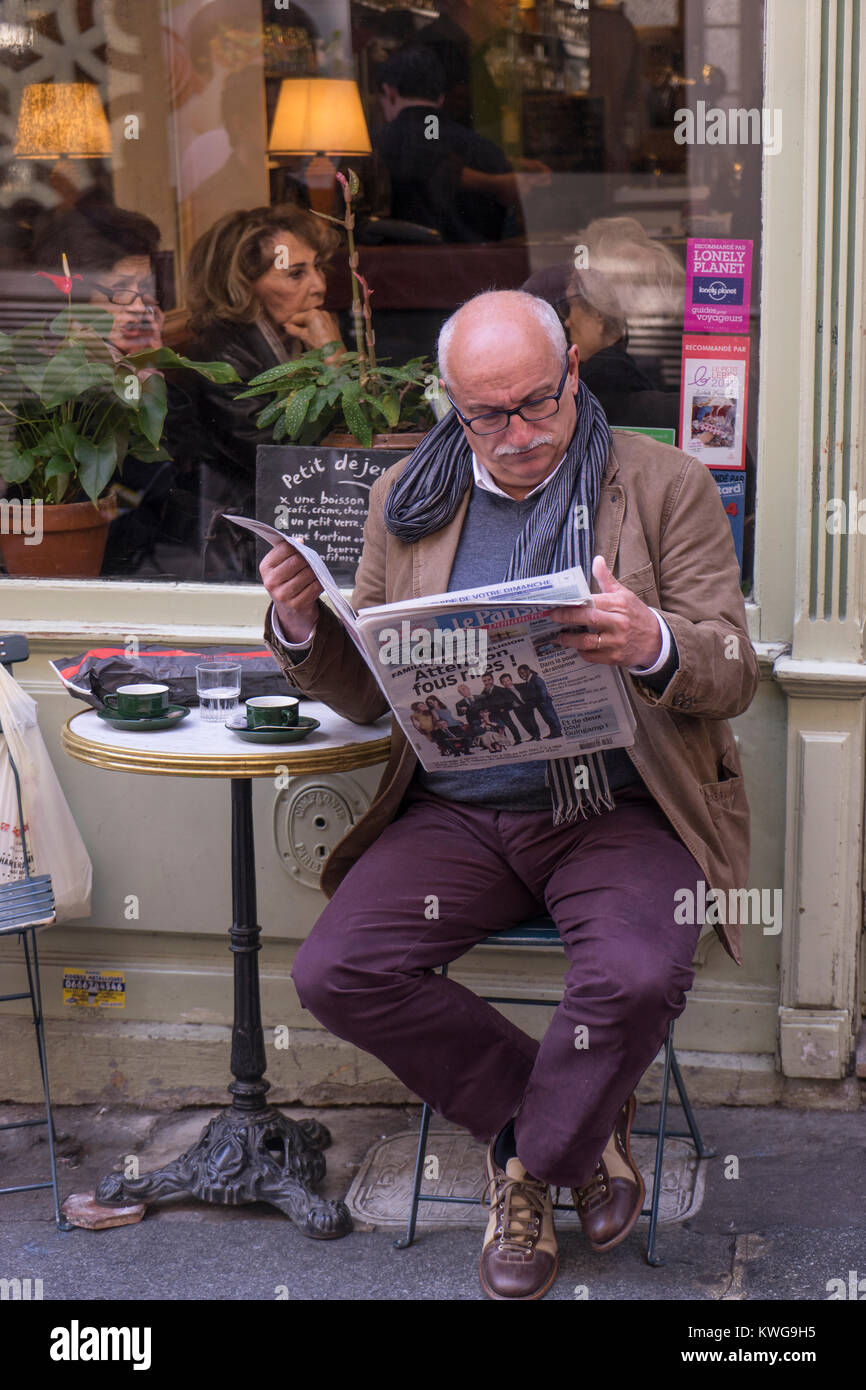 France, Paris, Man reading his morning paper in cafe Stock Photo